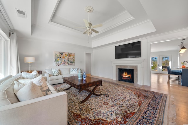 living room featuring visible vents, a raised ceiling, hardwood / wood-style floors, and a high end fireplace