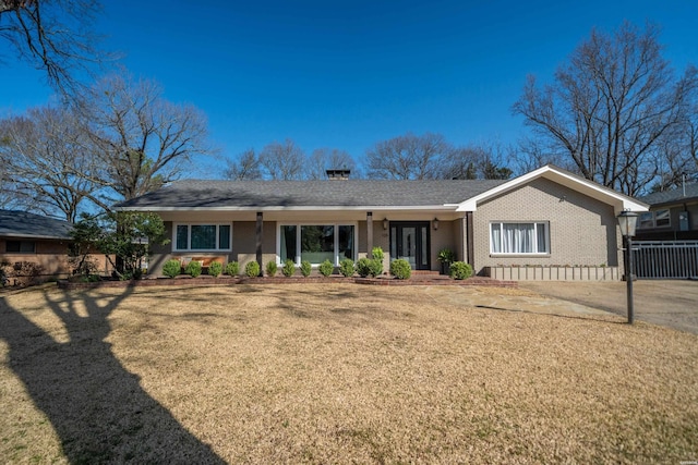 rear view of house featuring brick siding, a lawn, and fence