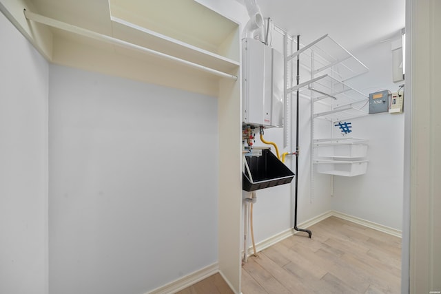 spacious closet with light wood finished floors and tankless water heater