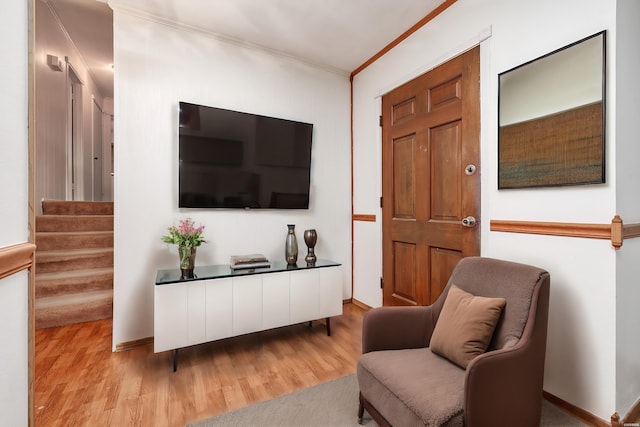 sitting room with stairway, light wood-style flooring, ornamental molding, and baseboards