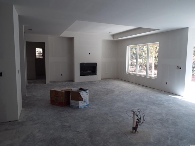 unfurnished living room with concrete flooring and a raised ceiling