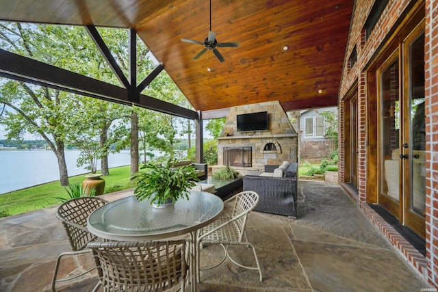 view of patio featuring a water view, an outdoor living space with a fireplace, ceiling fan, and outdoor dining area