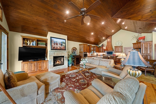 living room with a ceiling fan, wood ceiling, a stone fireplace, wood finished floors, and high vaulted ceiling