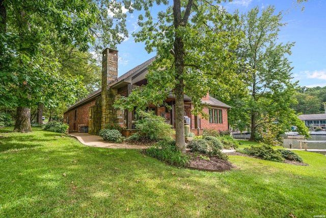 view of side of home with brick siding, a lawn, and a chimney