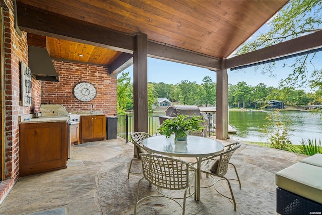 view of patio featuring outdoor dining space, a water view, a sink, and an outdoor kitchen