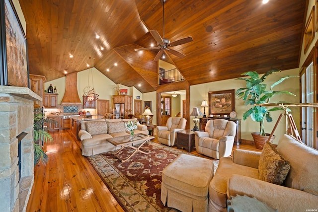 living room with wood ceiling, ceiling fan, a stone fireplace, high vaulted ceiling, and light wood-type flooring