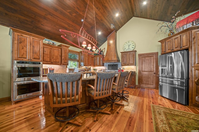 kitchen with wood ceiling, custom range hood, appliances with stainless steel finishes, and decorative backsplash