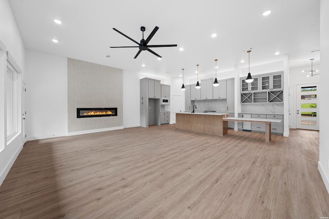 unfurnished living room featuring light wood-style flooring, a fireplace, a ceiling fan, and recessed lighting