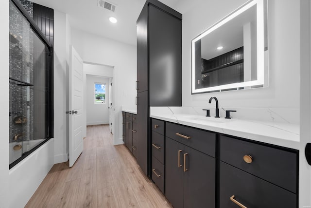 bathroom featuring bath / shower combo with glass door, recessed lighting, visible vents, vanity, and wood finished floors