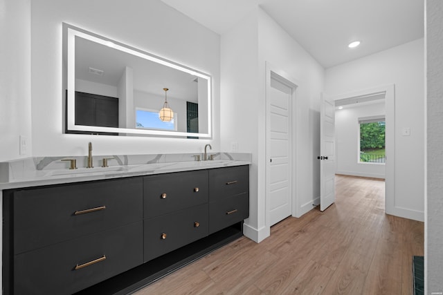 full bath featuring double vanity, a sink, baseboards, and wood finished floors