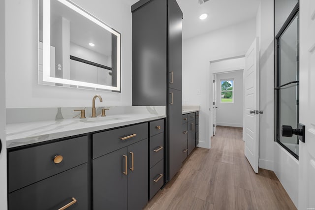 full bathroom with baseboards, bath / shower combo with glass door, wood finished floors, vanity, and recessed lighting