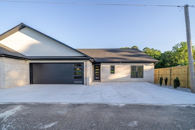 view of front of property with a garage, driveway, brick siding, and fence