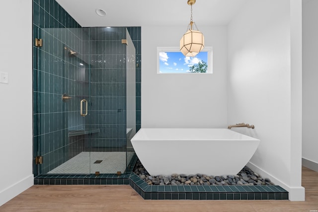 full bath featuring a soaking tub, a shower stall, baseboards, and wood finished floors