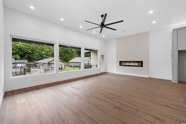 unfurnished living room featuring a large fireplace, ceiling fan, wood finished floors, and recessed lighting