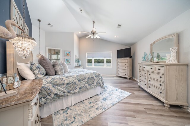 bedroom featuring lofted ceiling, visible vents, ceiling fan with notable chandelier, and light wood-style flooring