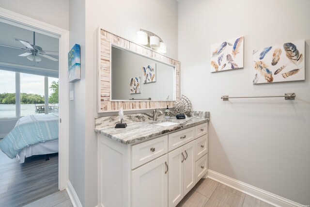 bathroom featuring a ceiling fan, connected bathroom, vanity, wood finished floors, and baseboards