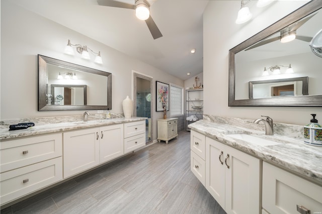 full bath with vaulted ceiling, two vanities, a sink, and a ceiling fan