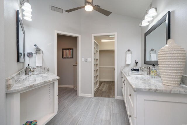 full bathroom featuring a spacious closet, visible vents, two vanities, and a sink