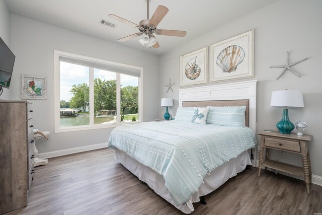 bedroom with a ceiling fan, baseboards, visible vents, and wood finished floors