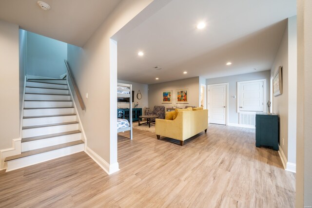 unfurnished living room featuring baseboards, stairway, recessed lighting, and light wood-style floors