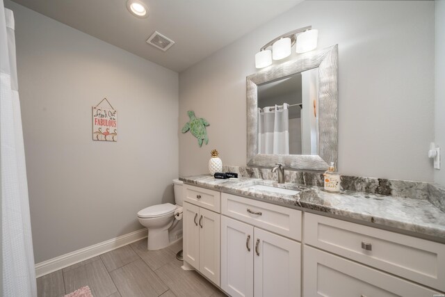 full bathroom featuring toilet, vanity, visible vents, and baseboards