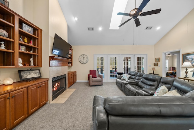 living room featuring light carpet, ceiling fan, visible vents, and a tiled fireplace