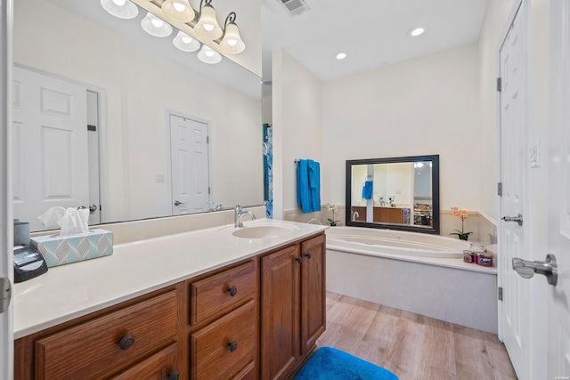 bathroom featuring visible vents, wood finished floors, a garden tub, vanity, and recessed lighting