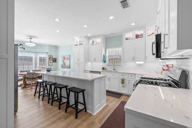 kitchen featuring a breakfast bar area, a sink, visible vents, appliances with stainless steel finishes, and a center island