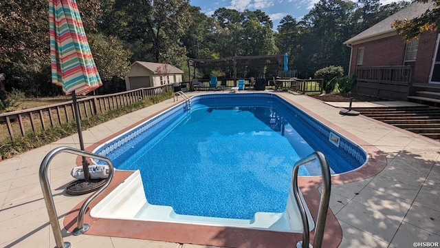 view of pool with a wooden deck, a patio, a fenced in pool, and an outbuilding