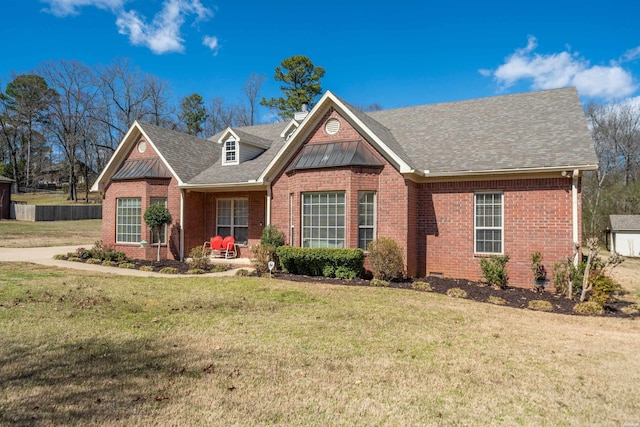 view of front facade with a shingled roof, a front yard, and brick siding