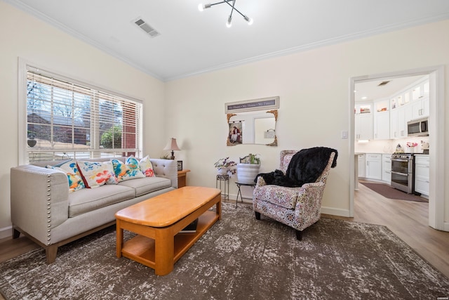 living area with baseboards, visible vents, wood finished floors, and ornamental molding