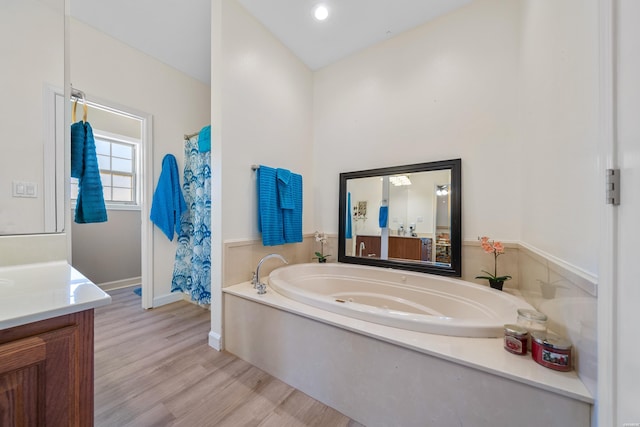 full bathroom featuring a bath, baseboards, wood finished floors, and vanity