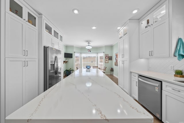 kitchen featuring appliances with stainless steel finishes, a kitchen island, white cabinetry, and decorative backsplash