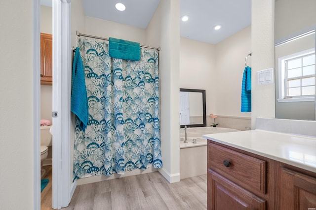 bathroom with a shower with shower curtain, toilet, wood finished floors, vanity, and a bath