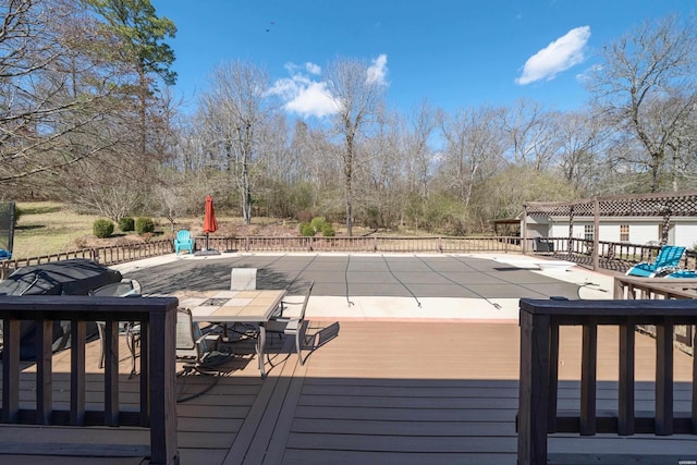 wooden terrace featuring a fenced in pool and outdoor dining space