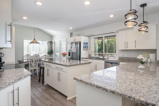 kitchen featuring white cabinets, a kitchen island, appliances with stainless steel finishes, light stone counters, and decorative light fixtures