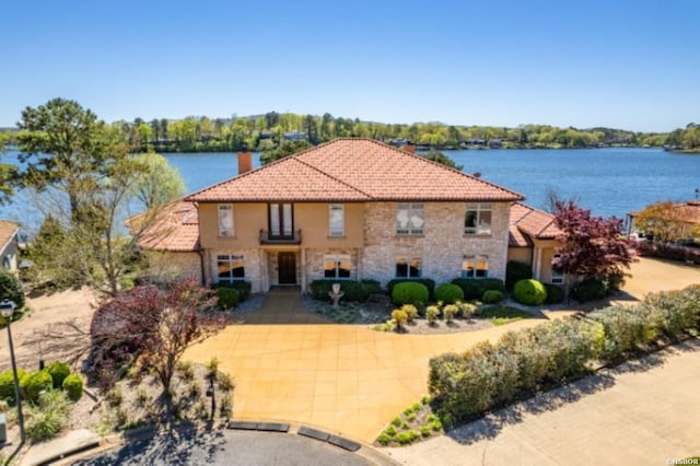 mediterranean / spanish-style home with a water view, stone siding, and a tiled roof