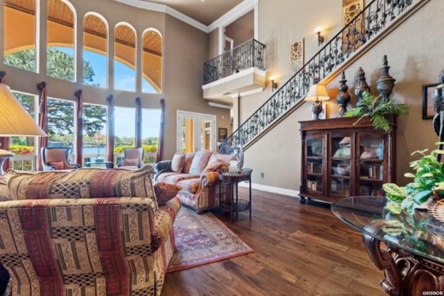 living area with baseboards, stairway, ornamental molding, dark wood-type flooring, and a high ceiling