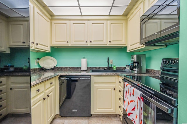 kitchen with a sink, light tile patterned floors, cream cabinetry, black appliances, and dark countertops