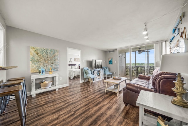 living room featuring ceiling fan, expansive windows, visible vents, baseboards, and wood finished floors