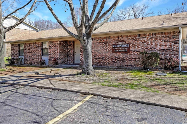 ranch-style home with brick siding and roof with shingles