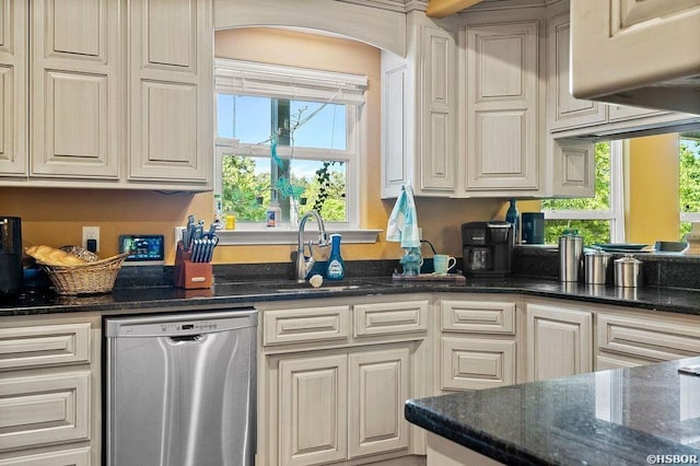 kitchen featuring dishwasher, dark stone counters, and a sink