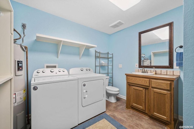 laundry room featuring visible vents, dark tile patterned flooring, electric water heater, separate washer and dryer, and a sink