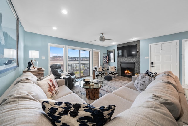 living area featuring a large fireplace, ceiling fan, wood finished floors, and recessed lighting