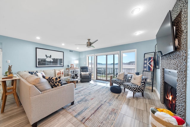 living area featuring a lit fireplace, a ceiling fan, and recessed lighting