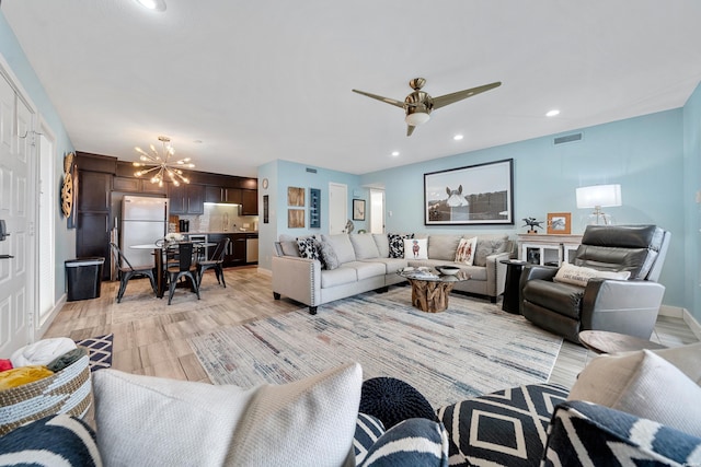 living room featuring recessed lighting, baseboards, visible vents, light wood-style flooring, and ceiling fan with notable chandelier