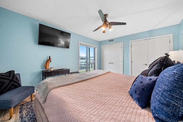 bedroom featuring ceiling fan, visible vents, multiple closets, and wood finished floors