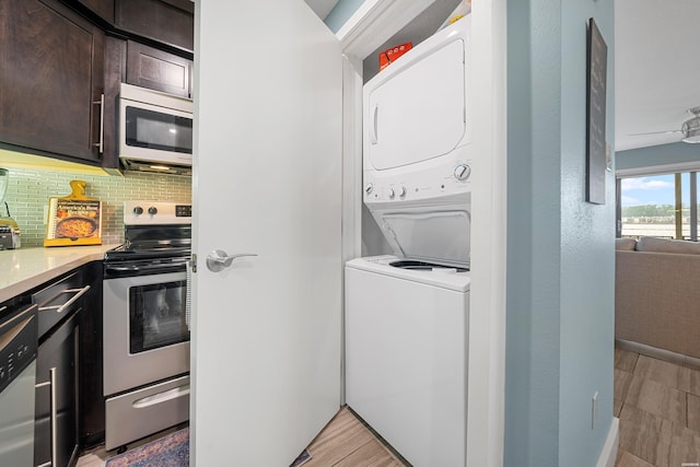 interior space with stainless steel appliances, dark brown cabinets, stacked washer and clothes dryer, and tasteful backsplash