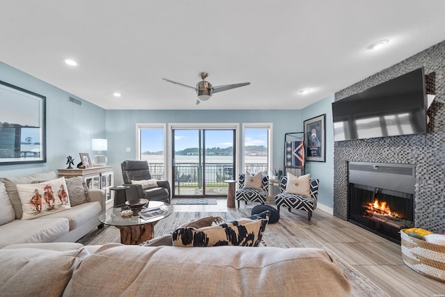 living area with baseboards, visible vents, a tiled fireplace, ceiling fan, and recessed lighting