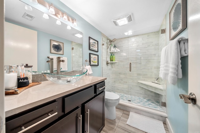 bathroom with visible vents, toilet, a shower stall, and vanity